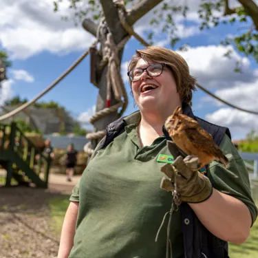 Zoo staff member smiling while holding an owl