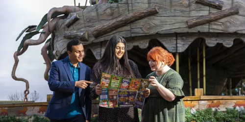 Three people looking Chessington World of Adventures Resort map