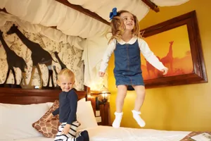 Children jumping on the bed in a giraffe themed room in the Chessington Safari Hotel