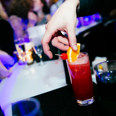 Image of cocktail being decorated with an orange wedge