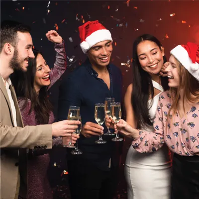 Group of people at a Christmas party smiling and holding champagne flutes